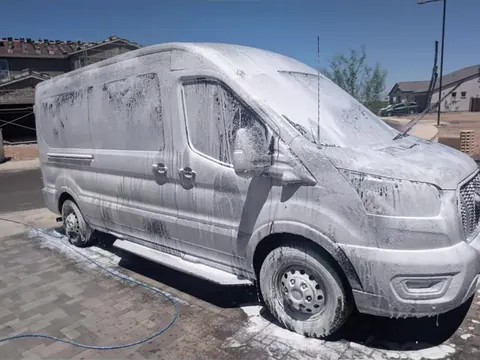 White Ford Transit van covered in wash foam
